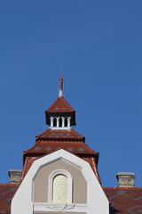 Art Nouveau roof turret with patterned terracotta tiles and slender spire under a clear blue sky, copy space above © Ionel