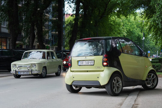 Yellow Smart Fortwo microcar and pale green Dacia 1100 classic sedan (licensed copy of Renault 8) - two eras of european microcars side by side. Subotica, Serbia - June 6, 2026