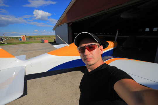 Young male pilot taking selfie by airplane