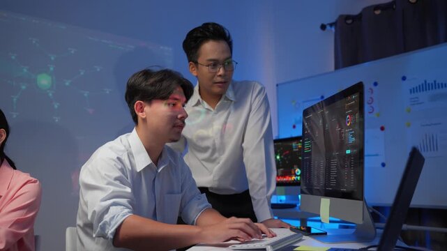 Financial analysts discussing cryptocurrency trading data on a computer screen in a modern office at night