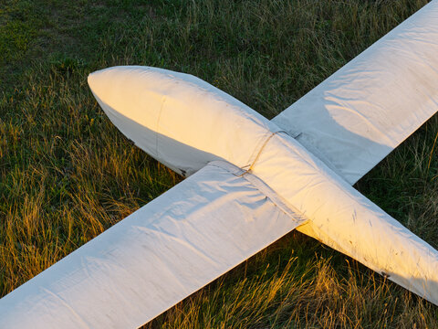 Aerial view of a white glider resting on a grassy field during the golden hour, United Kingdom.