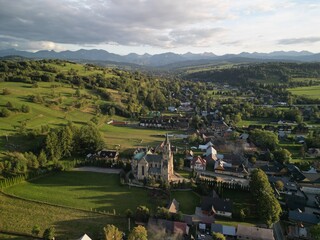 Chochołów - Polska  Panorama Chochołowa razem z kościołem i Tatrami na horyzoncie. Góry, pola, kościół, zdjęcie wykonane drone, lato, wiosna ,jesień © Konrad