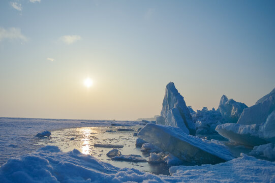 Large blue ice formations on frozen lake at winter sunset