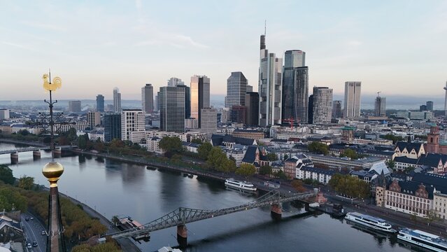 Aerial view of the Frankfurt am Main skyline with modern skyscrapers, the Main River, the Eiserner Steg bridge, and a golden weather vane, Frankfurt am Main, Hessen, Germany.