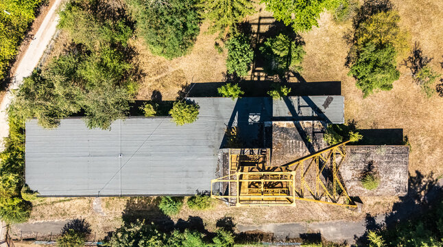 Aerial view of the abandoned Tiribesi-Akna coal mine headframe and industrial buildings amid summer vegetation in Batonyterenye, Hungary, within the Nograd coal basin.