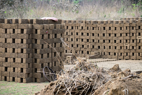 Rows of sun-dried mud bricks drying in an outdoor brickyard   