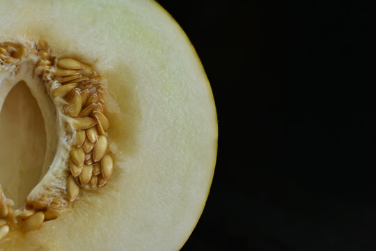Sweet melon cut of half with seeds.Yellow melon on black background. Food and fruit backgorund.Diet, health concept.