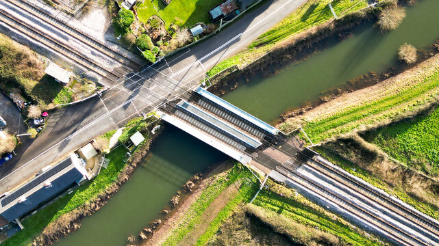 Aerial view of Athelney Railway Crossing spanning a narrow canal, surrounded by green fields and rural infrastructure in Athelney, England, United Kingdom.
