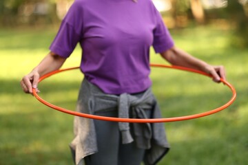 Senior woman exercising with hula hoop outdoors, closeup © New Africa