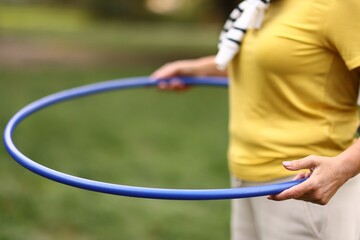 Senior woman exercising with hula hoop outdoors, closeup © New Africa