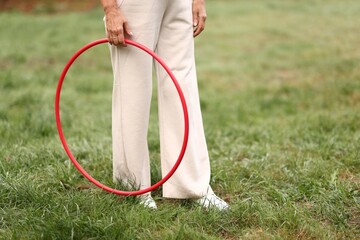 Senior woman with hula hoop in park, closeup. Space for text © New Africa