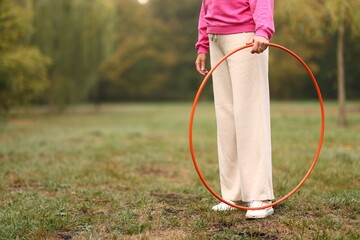 Senior woman exercising with hula hoop outdoors, closeup. Space for text © New Africa