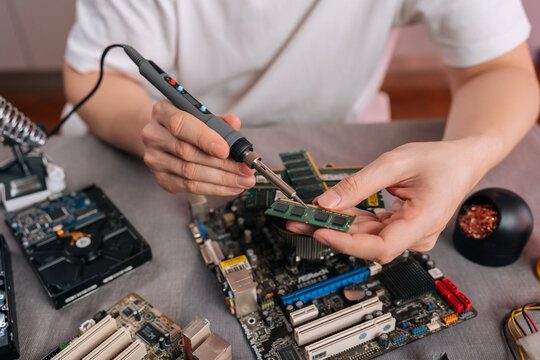 Close-up of technician repairing electronic component. Engineer soldering computer memory chip with precision tool. Technology maintenance, hardware upgrade workshop service concept.