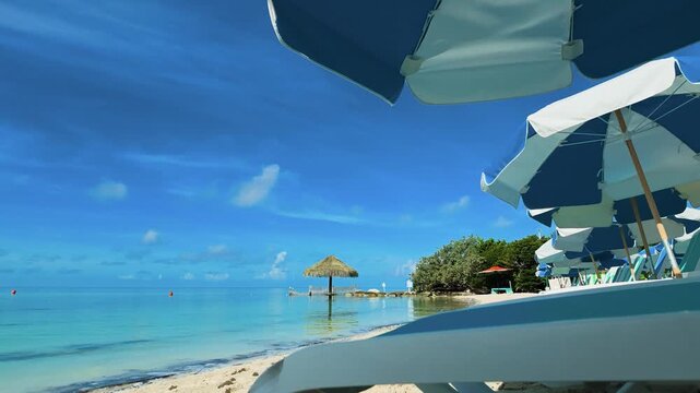 Tropical sand beach resort timelapse with moving clouds over turquoise ocean