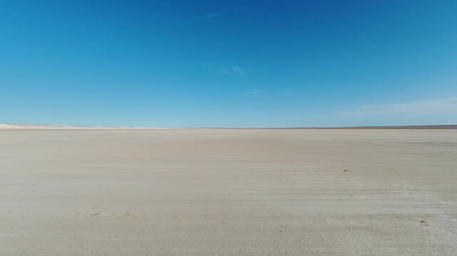 Ground-Level Journey Across the Empty Tuzbair Salt Plain Under Blue Sky