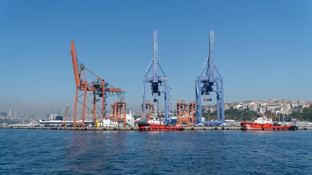 Haydarpasa Port in Kadikoy, Istanbul, Turkey, a cargo port with container cranes, red tugboats along the quay and rows of new cars waiting for shipping