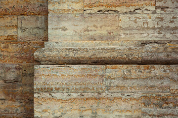 Close-up of a weathered stone wall with horizontal masonry blocks and a prominent architectural cornice molding. Ancient limestone surface with rust-colored stains and stratified layers for a historic © olgakudryashova