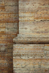 Close-up of a weathered stone wall with horizontal masonry blocks and a prominent architectural cornice molding. Ancient limestone surface with rust-colored stains and stratified layers for a historic © olgakudryashova