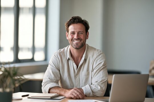 Friendly corporate headshot of a man looking at the camera in a bright workspace