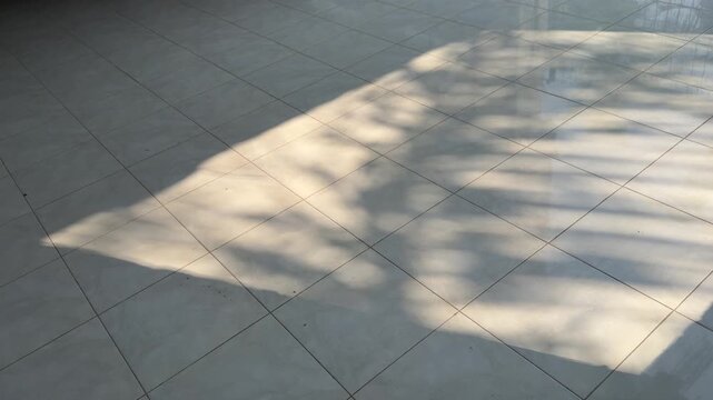 Hard sunlight shadow moving across square ceramic floor tiles, geometric architectural interior backdrop