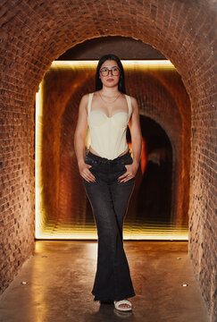 Photoshoot of a beautiful young Latina woman wearing glasses in a bar.
