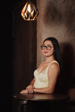 Photoshoot of a beautiful young Latina woman wearing glasses in a bar.