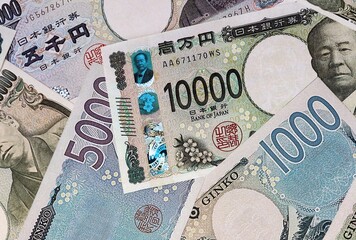 Japanese yen money bills in pile on table. Japan JPY currency banknotes background © Larysa