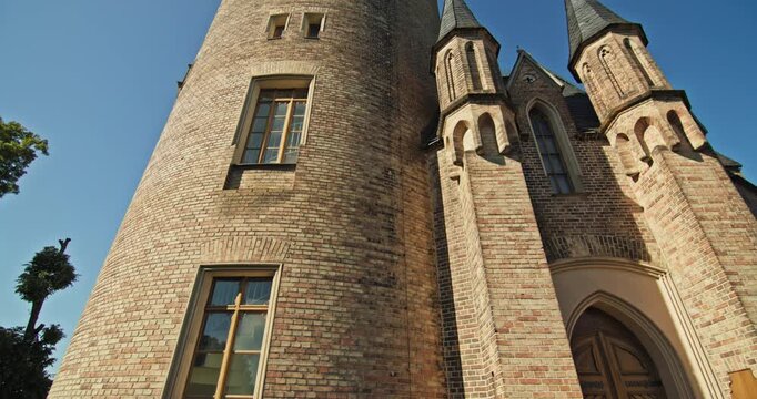 The pointed entrance arch and brick turrets of Flatow Tower in Babelsberg Park, Potsdam, Germany.