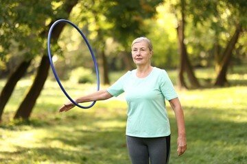 Senior woman exercising with hula hoop outdoors © New Africa