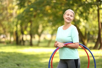 Senior woman with hula hoops in park, space for text © New Africa