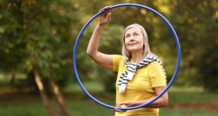 Senior woman with hula hoop in park © New Africa