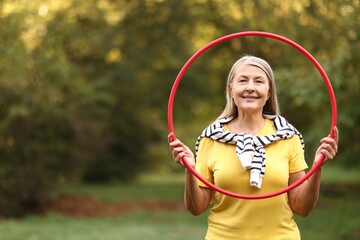 Senior woman with hula hoop in park, space for text © New Africa