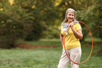 Senior woman with hula hoop in park, space for text © New Africa