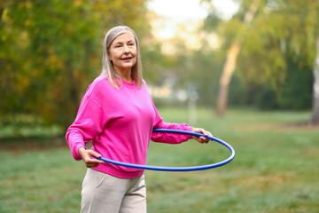 Senior woman exercising with hula hoop outdoors © New Africa