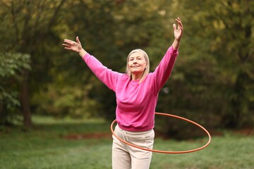 Senior woman exercising with hula hoop outdoors © New Africa