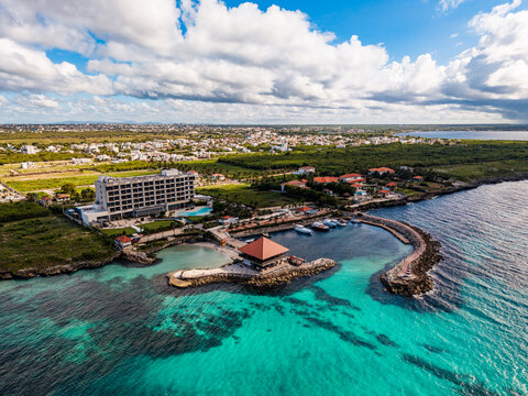 Aerial view of Muelle 7 La Romana, a pier with a building, surrounded by turquoise Caribbean Sea, boats, and a coastal resort area in La Romana, La Romana, Dominican Republic.