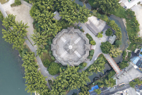 Aerial view of a traditional octagonal pavilion surrounded by lush bamboo trees and greenery, situated near a river in Guilin, Guangxi, China.