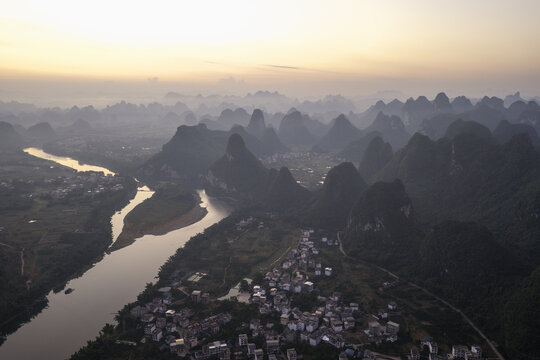 Aerial view of karst mountains and the winding Li River flowing past a village in Guilin, Guangxi, China.