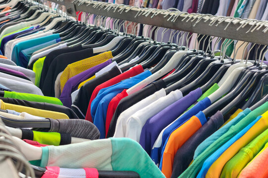 Colorful secondhand clothes hanging on market rack, vintage fashion and thrift shopping at outdoor clothing stall