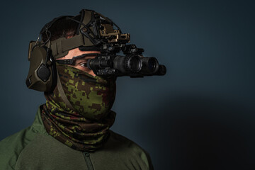 Profile portrait of a tactical operator wearing head harness mounted dual monocular night vision optics, ballistic eye protection and active headset © Dmitri