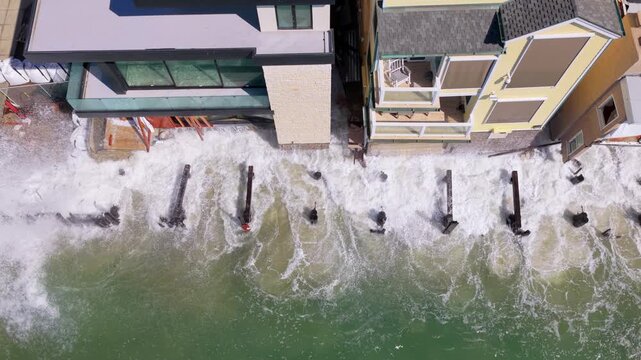 Static top down view of storm surf pounding sandbags and broken bulkhead pilings below homes on the Peninsula after Tropical Storm Rachel. Long Beach, California, USA - October 15, 2026