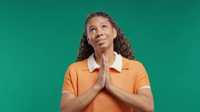 Hopeful young woman praying with clasped hands. Teenage girl asking for support, good luck, strength and success before important moment.