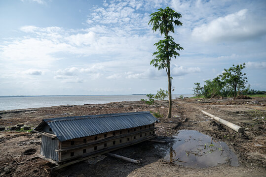 Chilmari, Rangpur Division, Bangladesh - 20 June 2025: View of a small wooden structure with a corrugated metal roof on the muddy riverbank under a cloudy sky.
