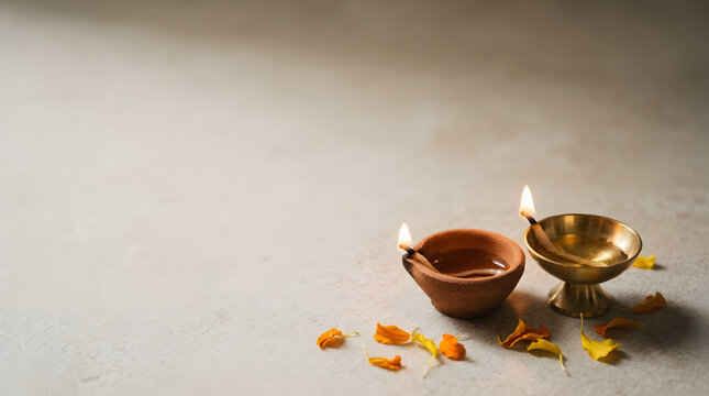 Two glowing oil lamps with marigold flower petals for the Diwali festival celebration