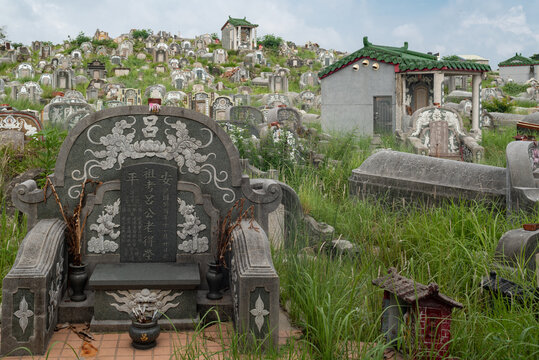 Tainan, Taiwan - 12 May 2015: View of traditional Chinese graves and ornate stone tombstones scattered across a grassy hillside in Tainan, Taiwan.