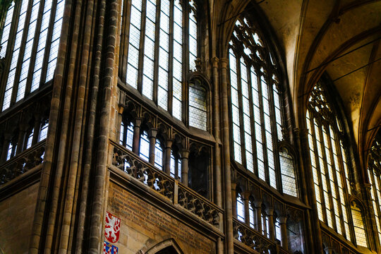 Prague, Czechia - 05 October 2026: View of St. Vitus Cathedral featuring intricate Gothic stone arches, tall stained glass windows, and ornate architectural details in the interior.
