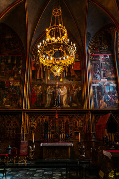 Hlavni mesto Praha, Czechia - 05 October 2026: View of St. Vitus Cathedral interior featuring a large ornate golden chandelier hanging above the altar and detailed religious murals.