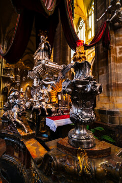 Prague, Czechia - 05 October 2026: View of the ornate silver tomb of St. John of Nepomuk inside St. Vitus Cathedral, featuring intricate baroque metalwork and red velvet drapery.