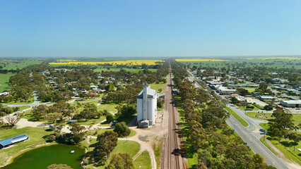Tatiara, South Australia, Australia – 4K aerial drone view of rural Australian township, historic grain silos, railway line, tree-lined highway, green farmland and golden yellow canola fields © Vistalen