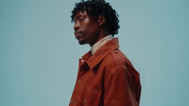 Adult in a rust structured jacket against pale blue